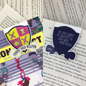 purple and green creative crest laminated magnetic bookmark reading "choose your weapon" on front and "the chief enemy of creativity is good sense" on back